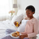 pregnant woman with orange juice and pastry in bed