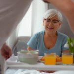 Contended lady looking at breakfast while lying in the bed